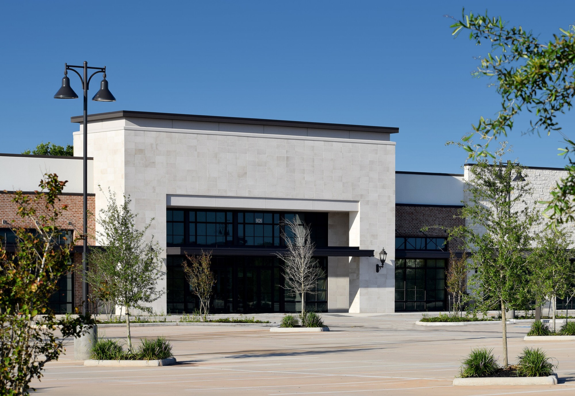 Premium stone-clad commercial storefront with dark-framed glazing — example of Comanche Glass installation
